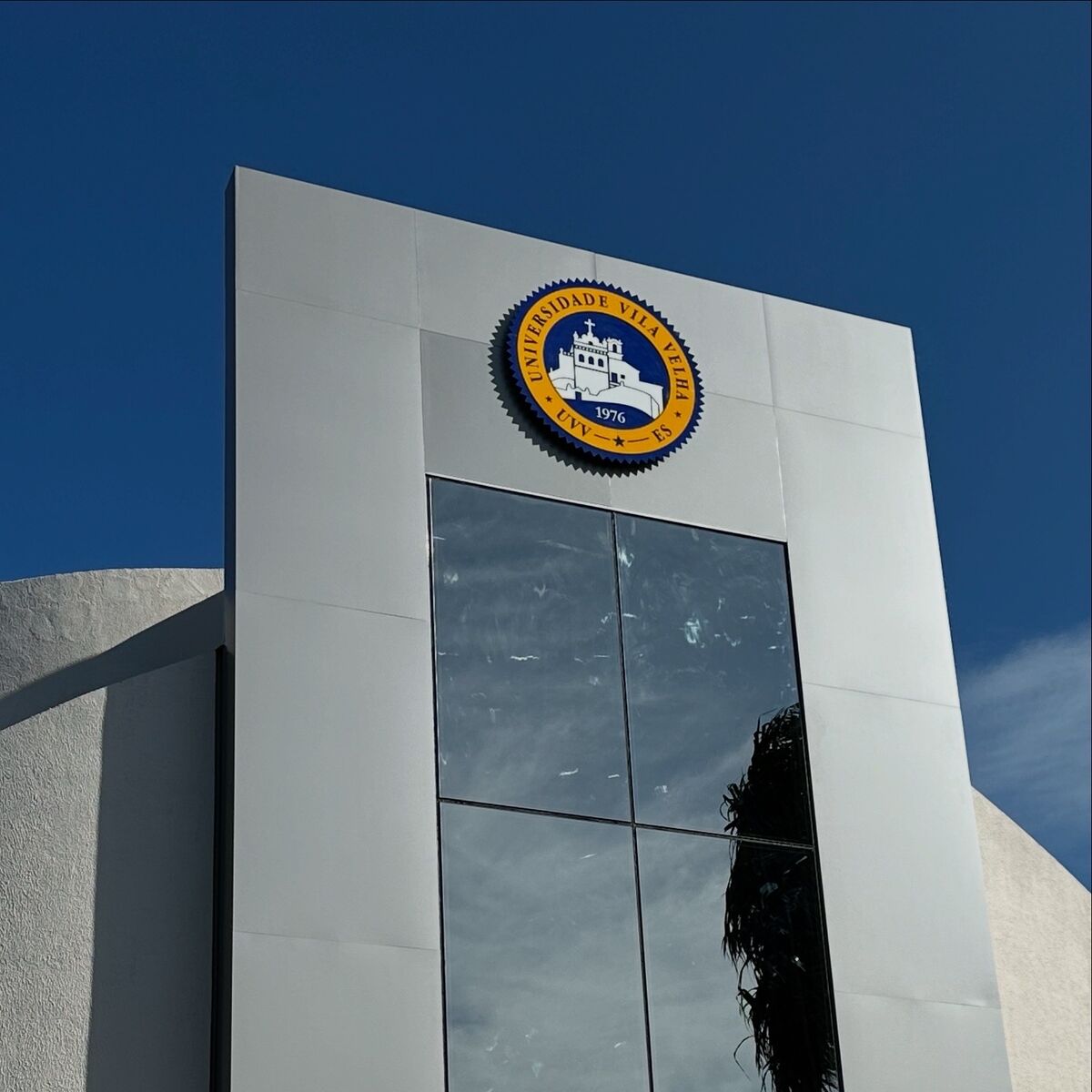 Fachada de prédio revestida em ACM com logo redondo em alto relevo.
