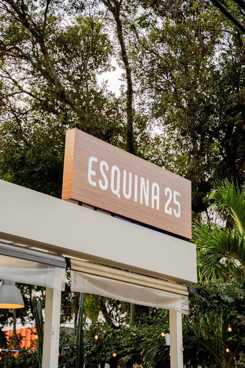 Letreiro caixa moderno com letras brancas e fundo amadeirado, para identificação comercial.