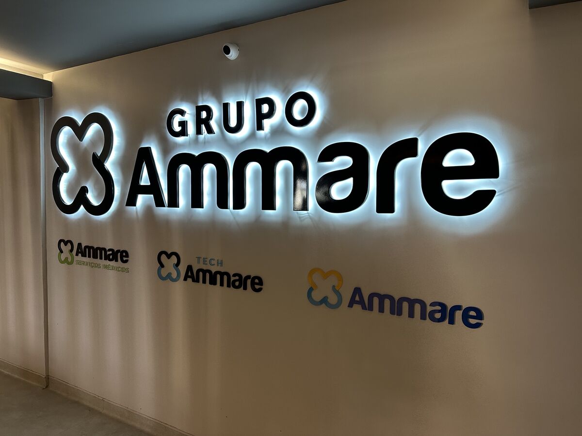 Identidade visual retroiluminada do Grupo Ammare em parede interna corporativa.